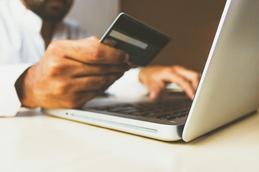 Person using a laptop holding a credit card to shop online